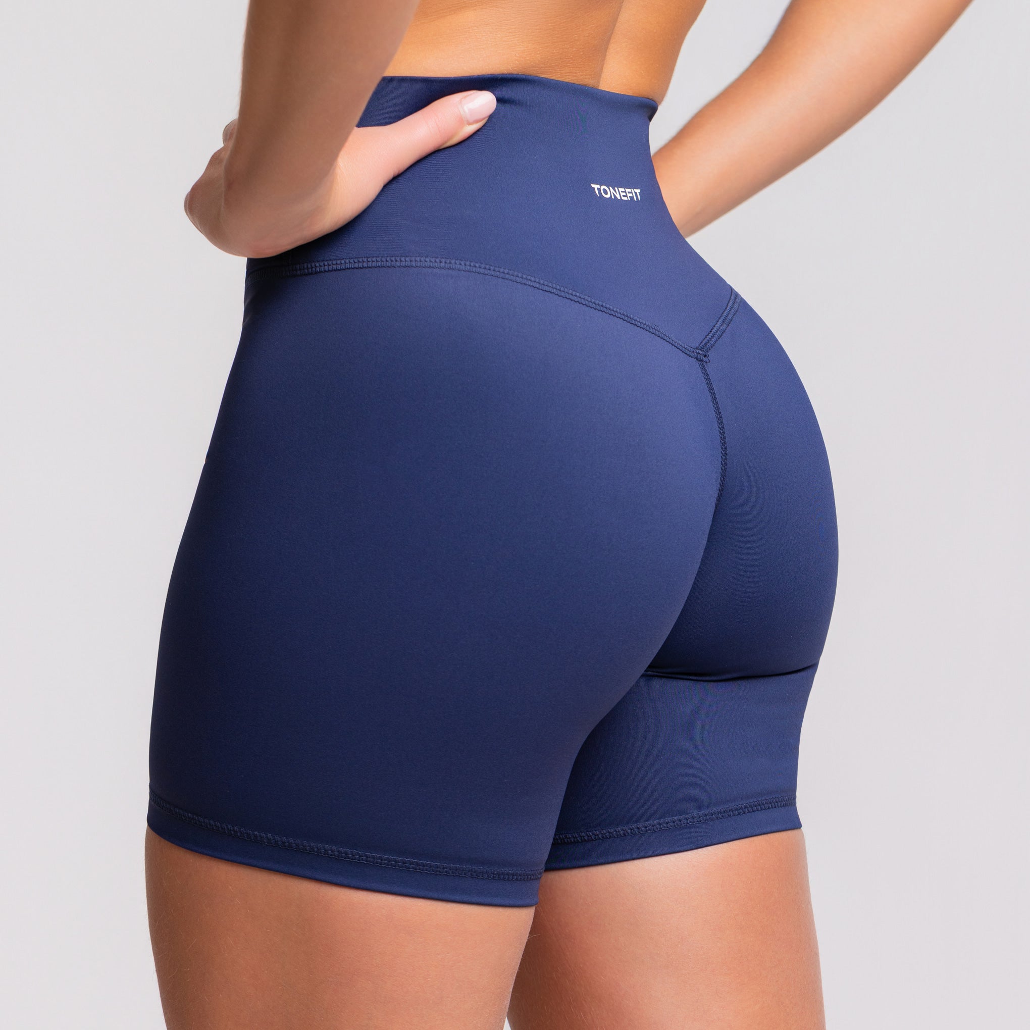 Front view of woman wearing TONEFIT V-Waist 5" shorts in Deep Sapphire color
