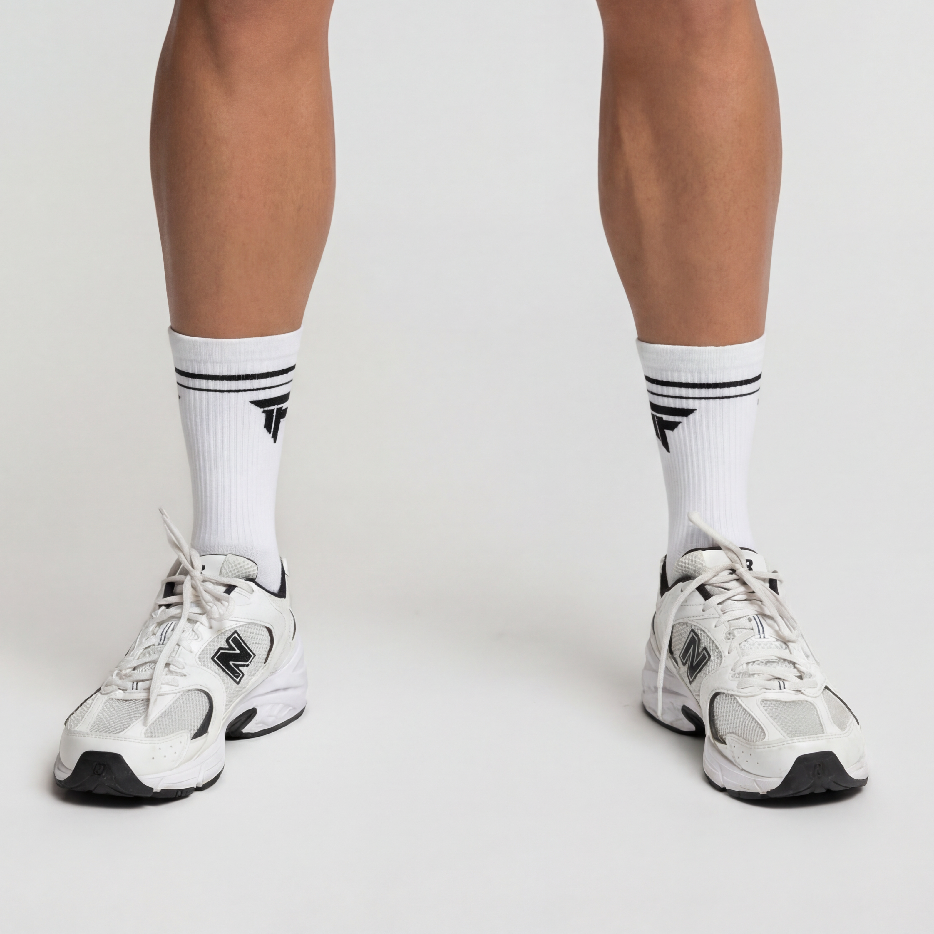 Man wearing New Balance sneakers with white athletic socks, showcasing essential GEAR for performance.