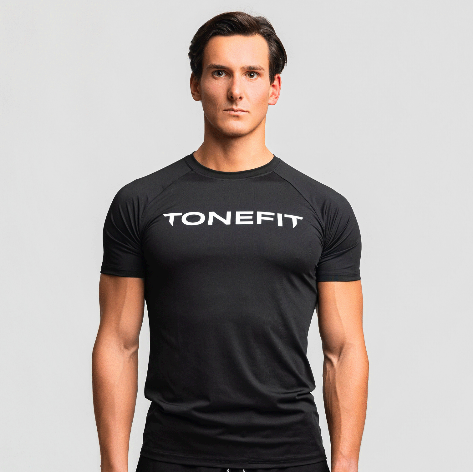 Front view of man wearing black TONEFIT Raglan Performance Tee with logo print