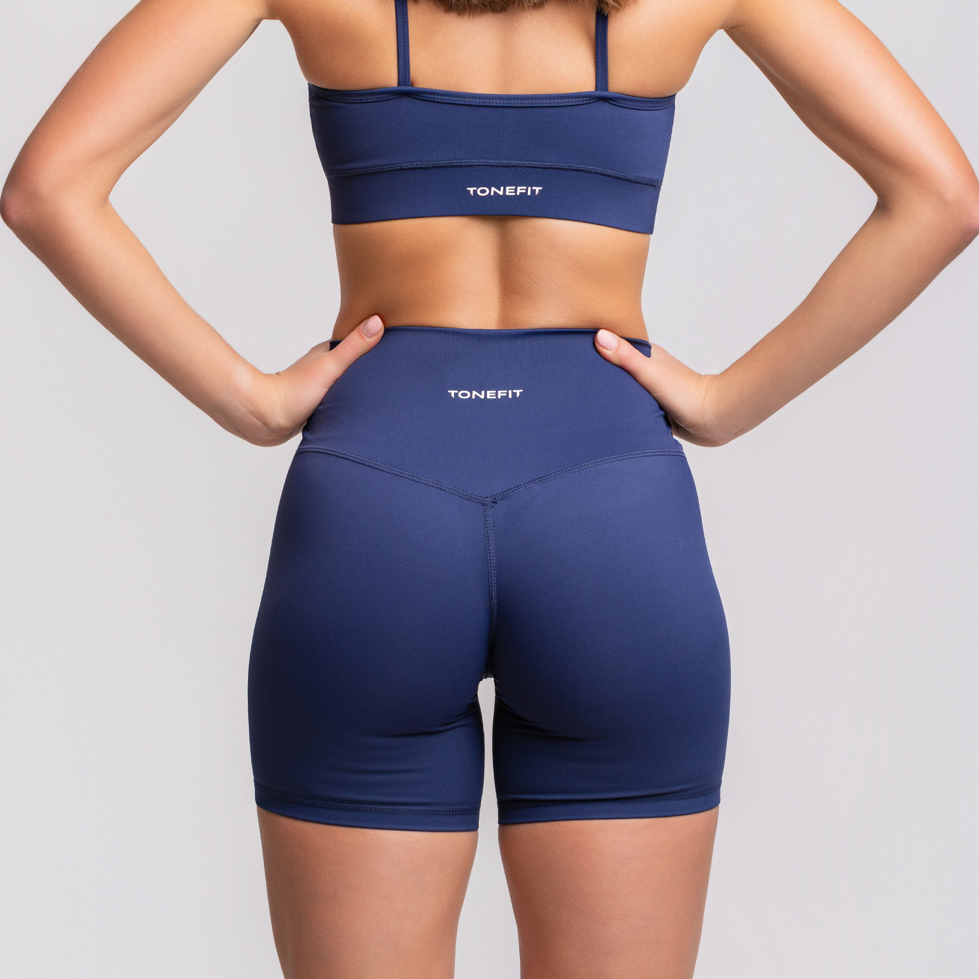 Back view of TONEFIT women’s 5-inch V-waist navy blue performance shorts with sculpted fit