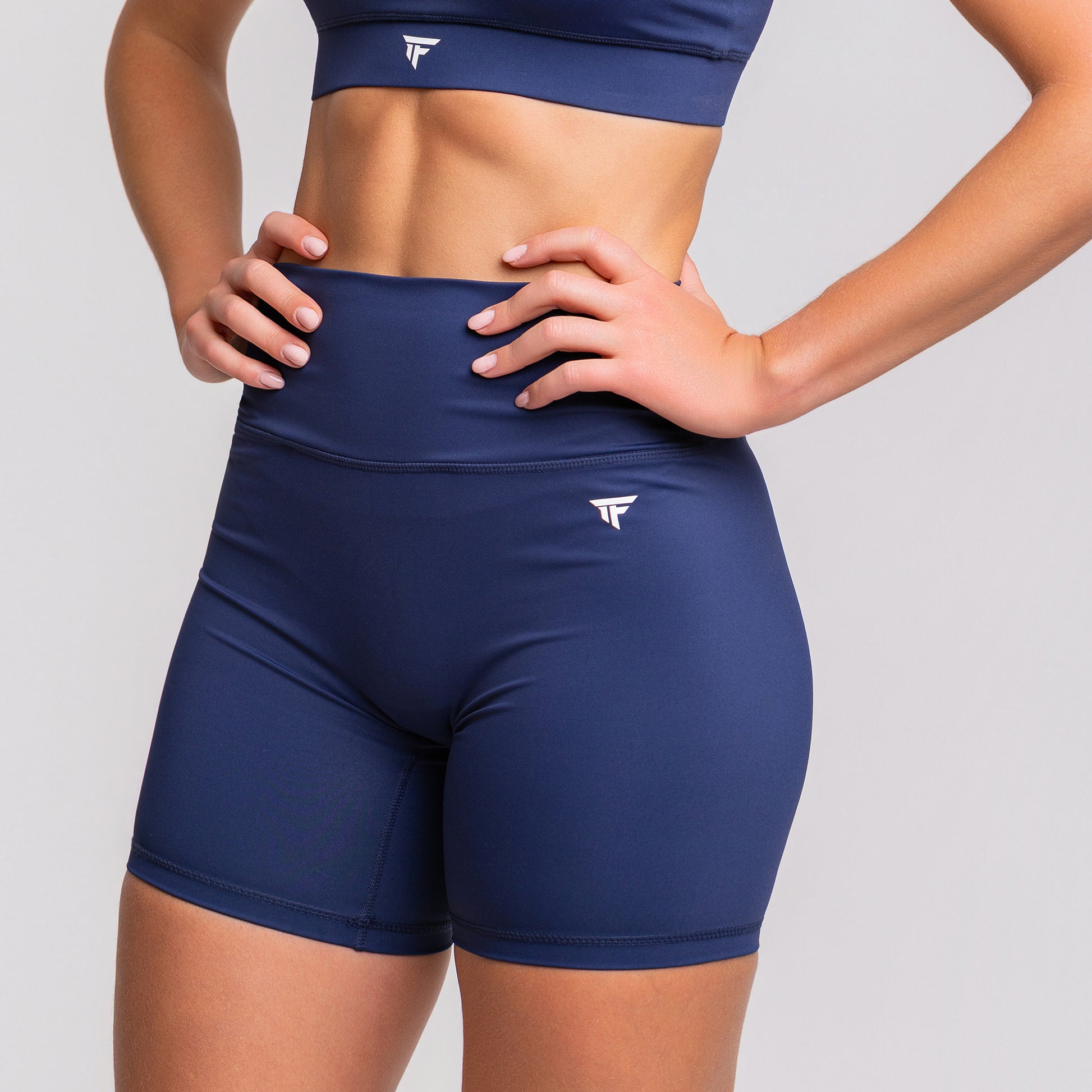 Left front angle of TONEFIT women’s 5-inch V-waist navy blue performance shorts highlighting fit and waistband