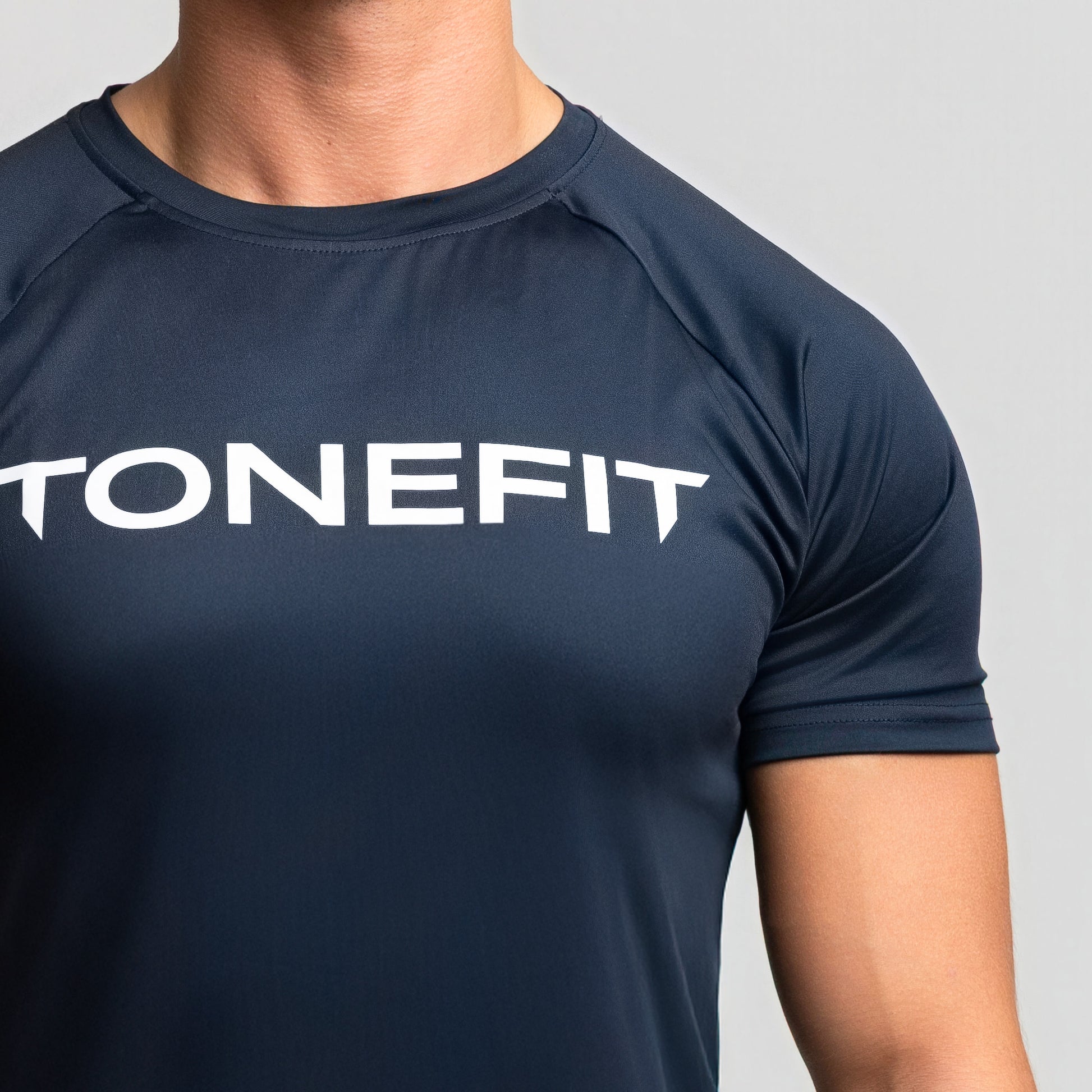 Detail shot of TONEFIT dark sapphire men’s t-shirt focusing on chest logo and material texture.