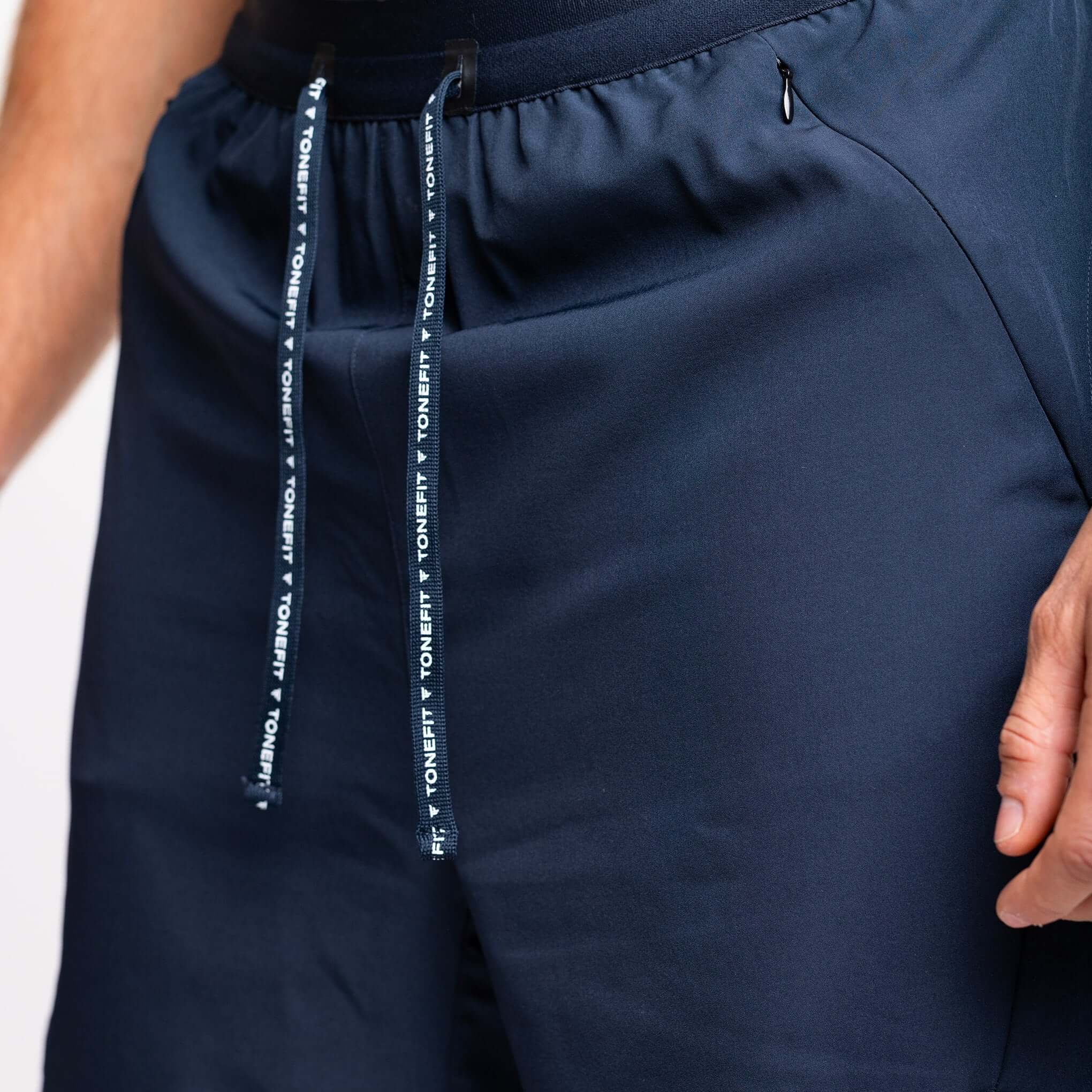 Close-up of the 2-in-1 hybrid training shorts waistband and drawstring from TONEFIT in navy blue.