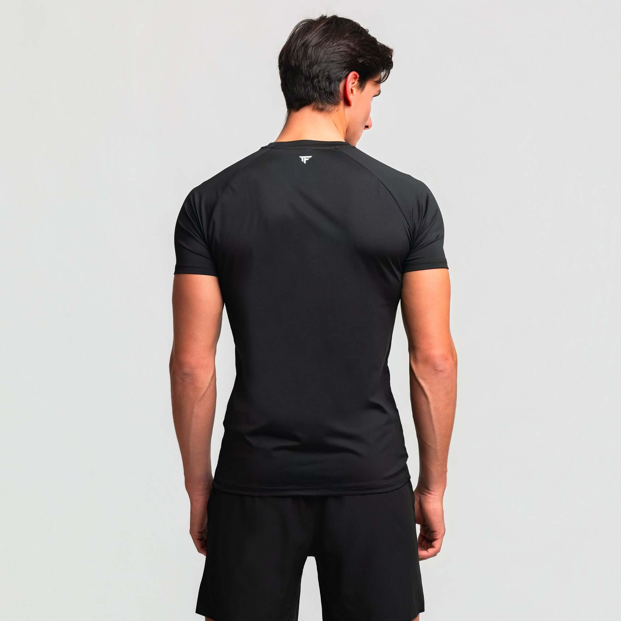 Back view of a man wearing Kinetic Raglan athletic fit gym shirt, showing seamless design and performance features.