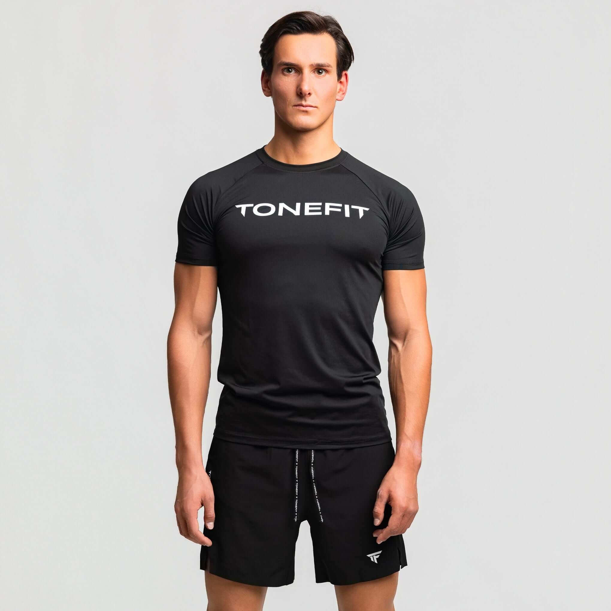 Man wearing TONEFIT Kinetic Raglan athletic fit gym shirt in black, ideal for maximum mobility during workouts.