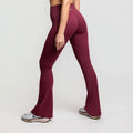 High waisted flare leggings in maroon color worn from the side, showcasing their flared hem and sleek silhouette.
