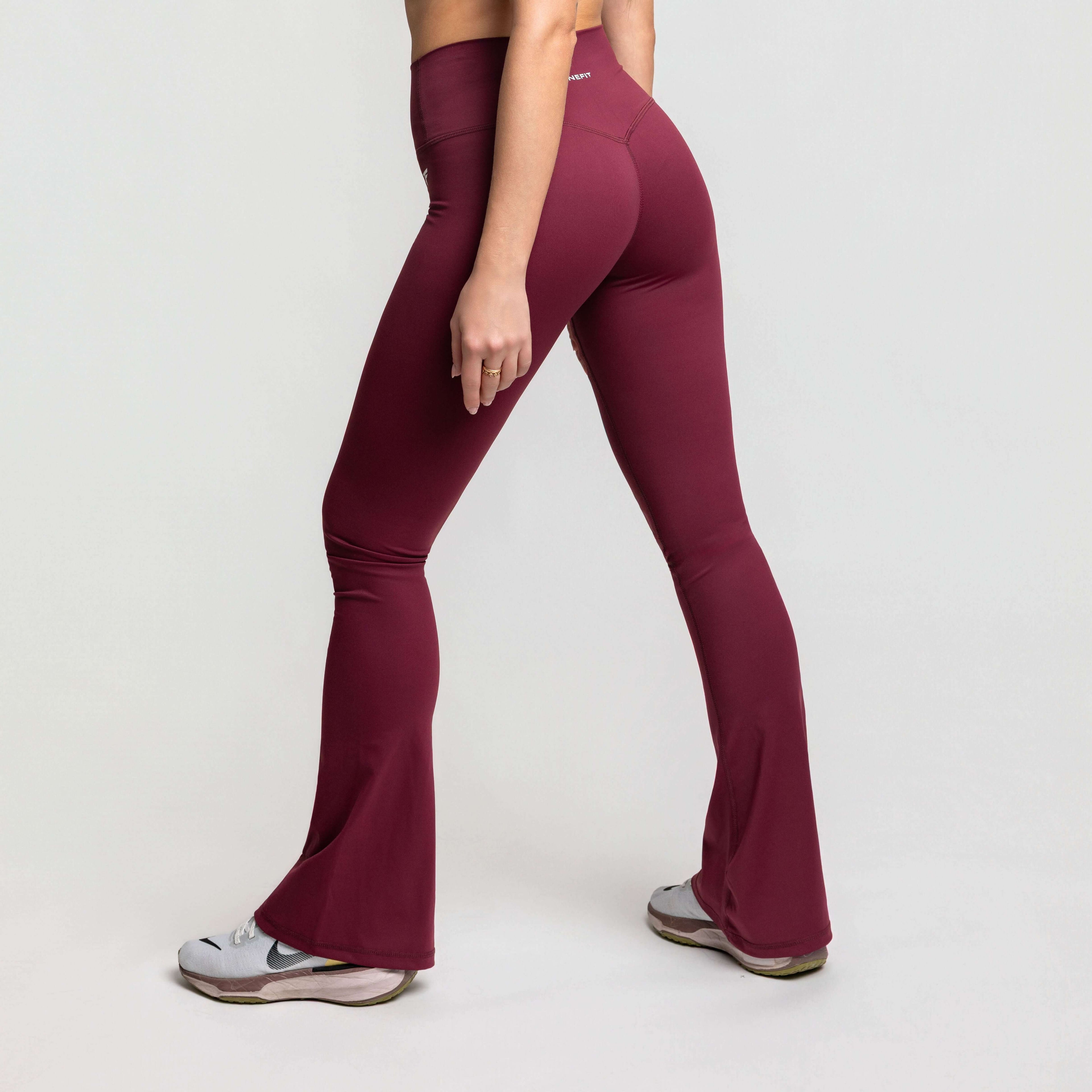 High waisted flare leggings in maroon color worn from the side, showcasing their flared hem and sleek silhouette.