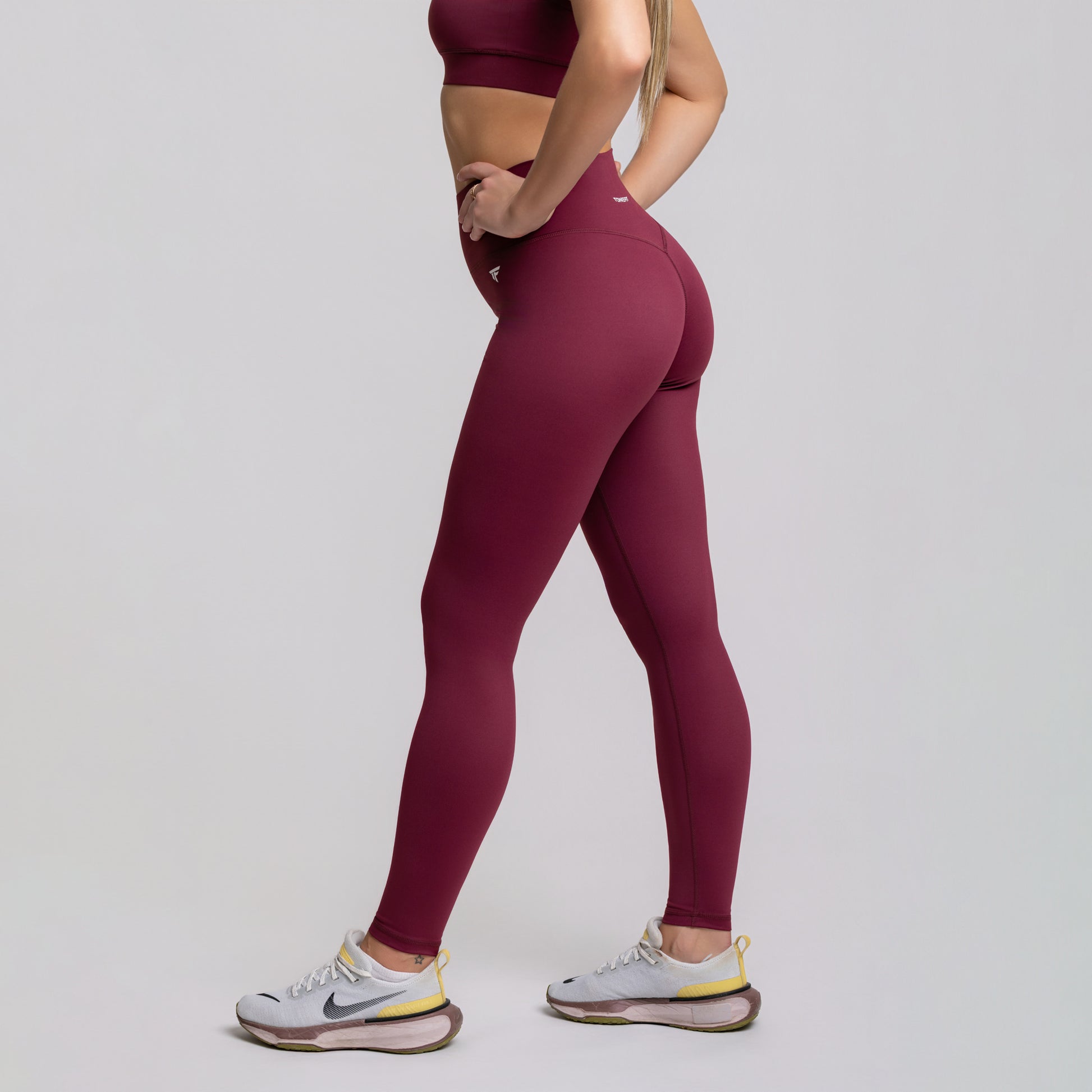 Side view of Dark Plum TONEFIT leggings showing V-waist design and leg-contouring stretch