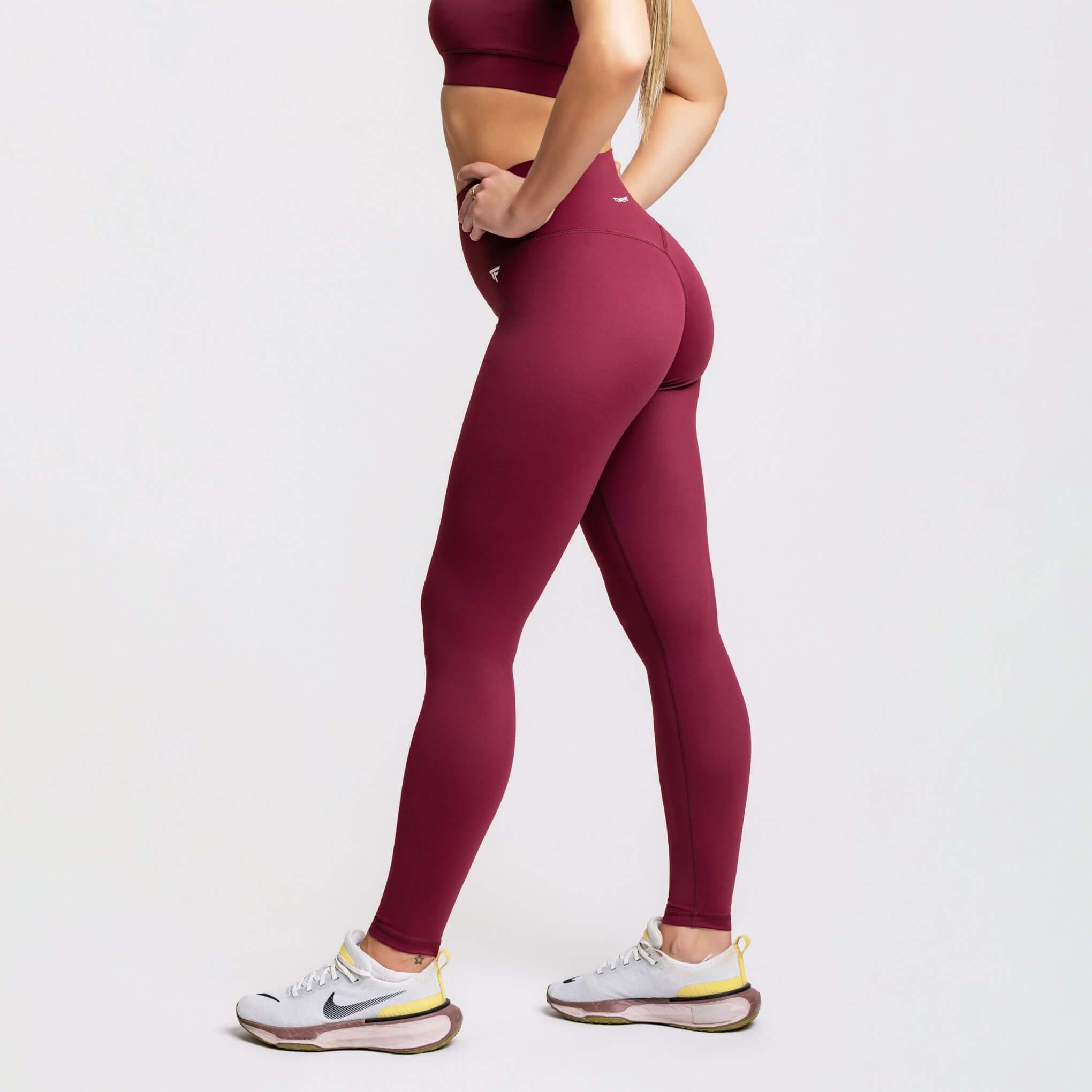 A person wearing V-waist sculpt leggings in burgundy, showcasing high-waist performance and style.