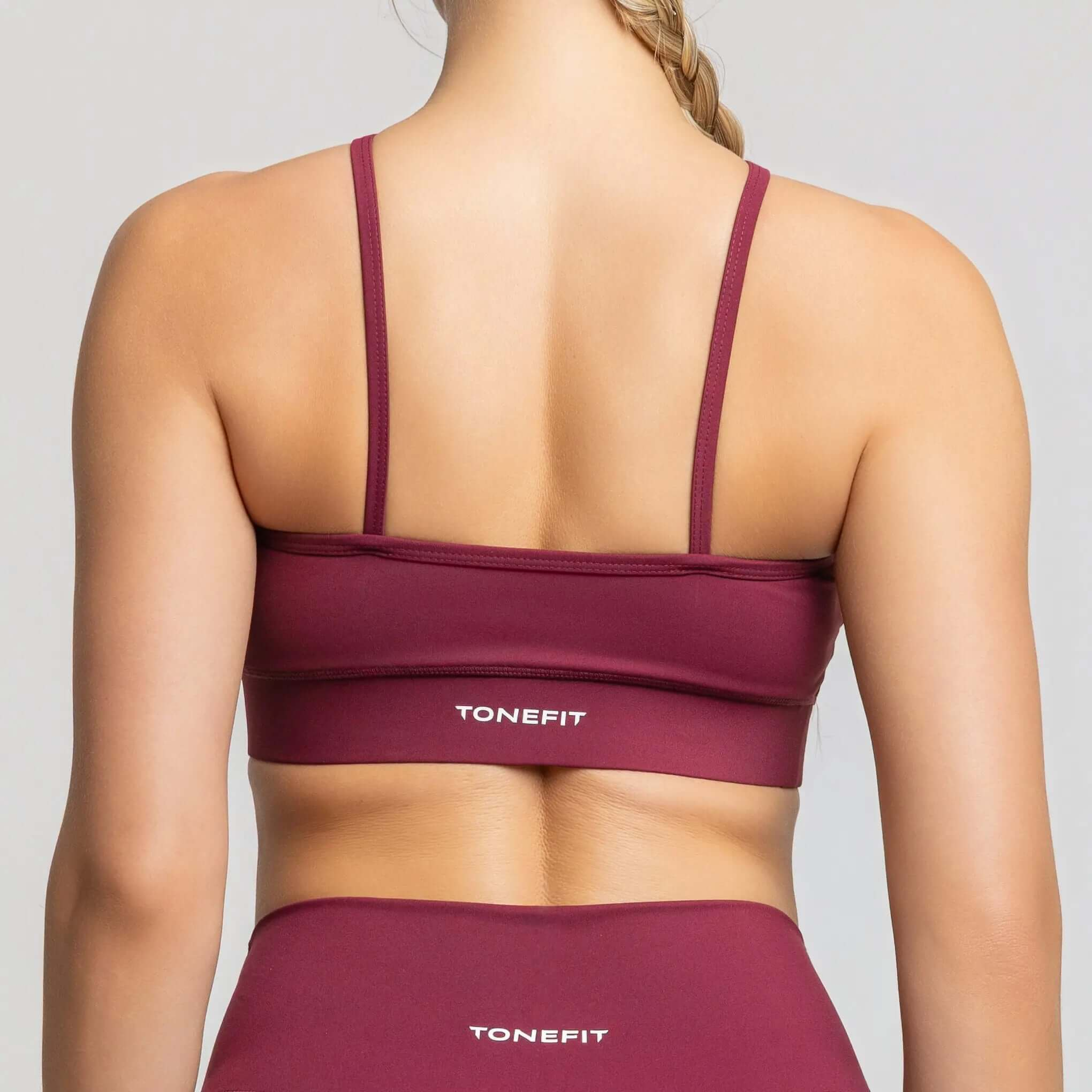 Halter neck sports bra by TONEFIT in burgundy, showcasing the back design and supportive fit.