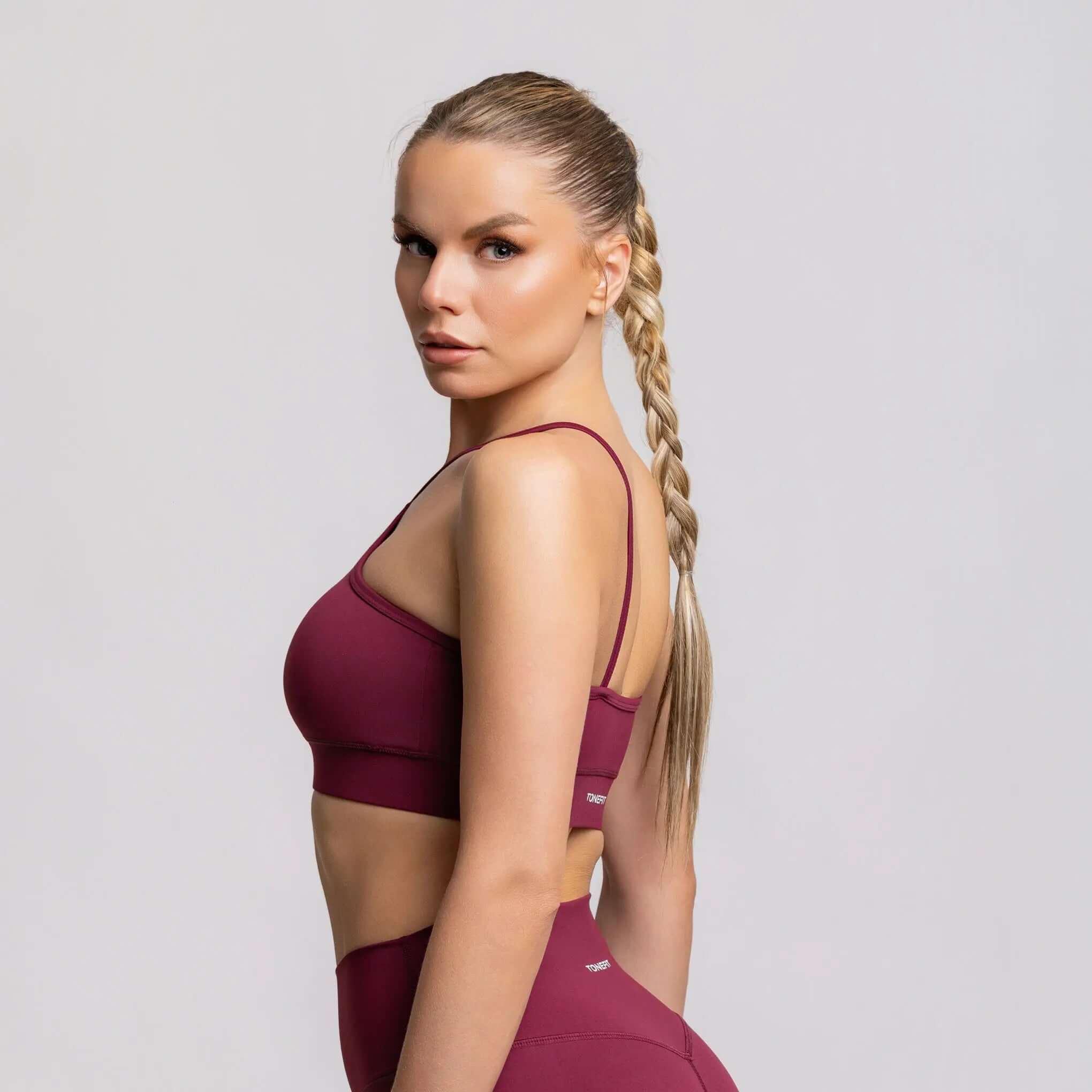 Model showcasing the Halter Neck Sports Bra in burgundy, highlighting its design and fit for active wear.